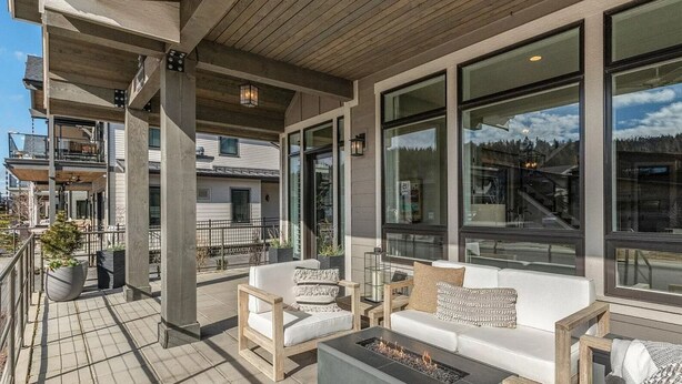 A covered outdoor seating area with wooden furniture and a fire pit.
