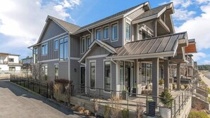 A modern two-story house with a covered porch and a fenced yard.