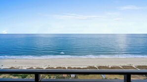 A beach view from a balcony with a clear sky.