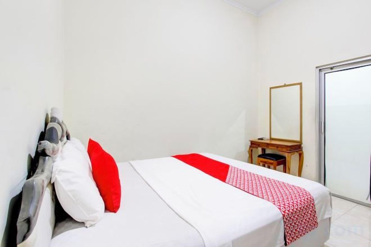 Une chambre à coucher avec un lit, un miroir et une petite table.