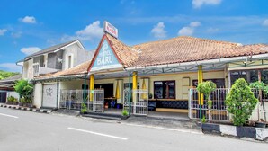 A hotel with a tiled roof, a covered entrance, and a signboard. - Hotel O Jalan Malioboro Near Stasiun Tugu Yogyakarta Formerly Hotel Baru (Yogyakarta)