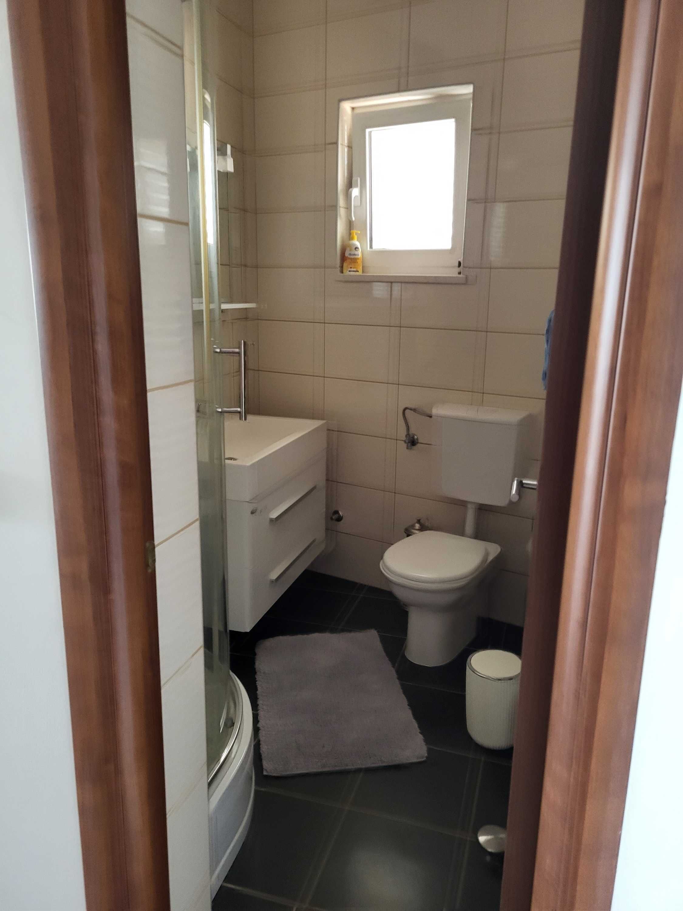 Ein kleines Badezimmer mit Toilette, Waschbecken und einem kleinen Fenster.
