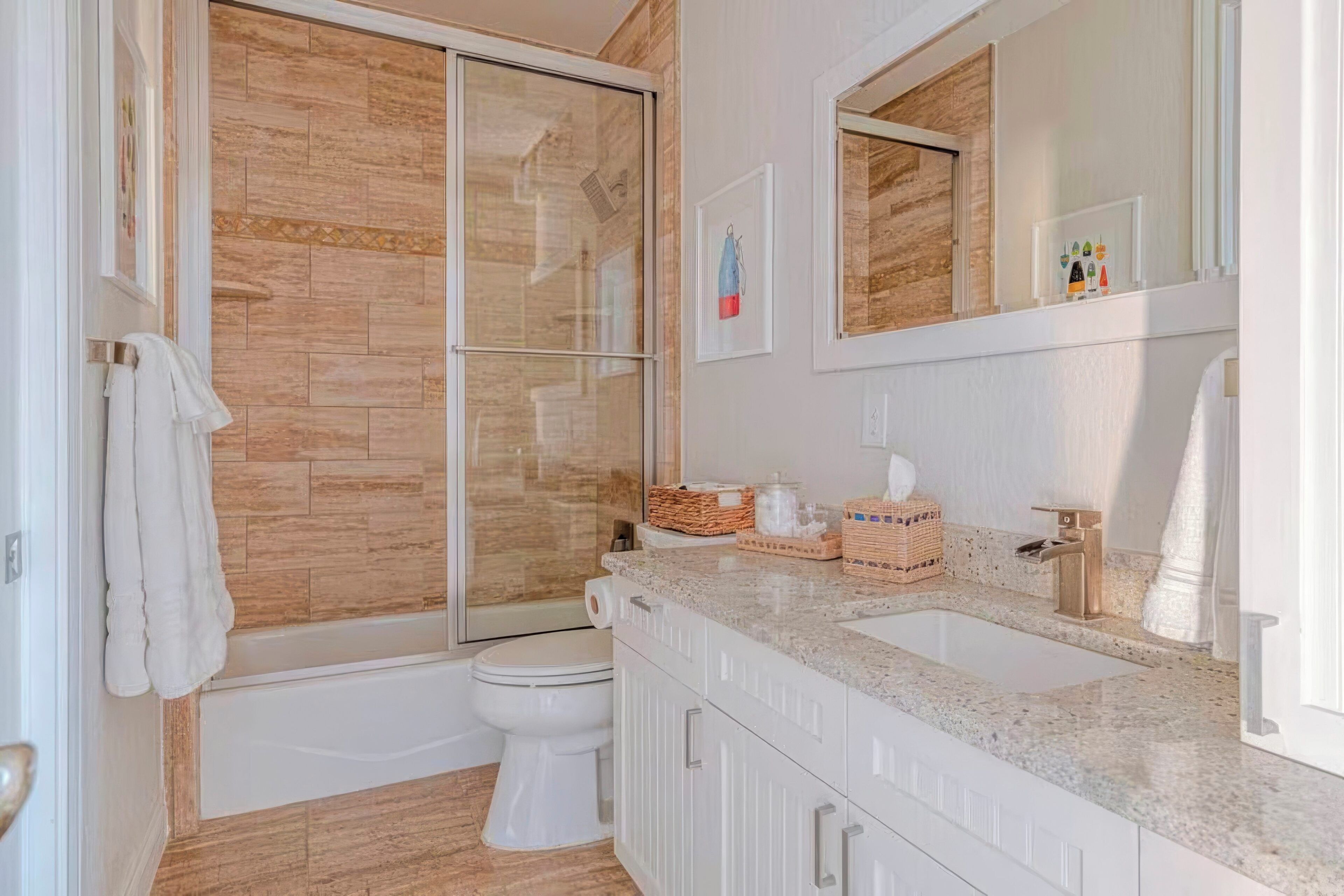 A modern bathroom with a glass-enclosed shower, a white toilet, and a granite countertop with a sink.
