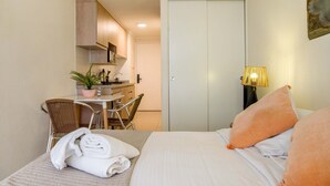 Una camera d'albergo con un letto, una scrivania con una sedia, una pianta in vaso e un armadio.