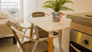 Una cucina moderna con zona pranzo, una TV a schermo piatto montata a parete, un vaso di felce sul tavolo e vista all'esterno da una finestra.