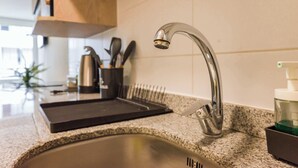 Una cucina con lavello in acciaio inossidabile, un rubinetto moderno e un piano di lavoro in granito.