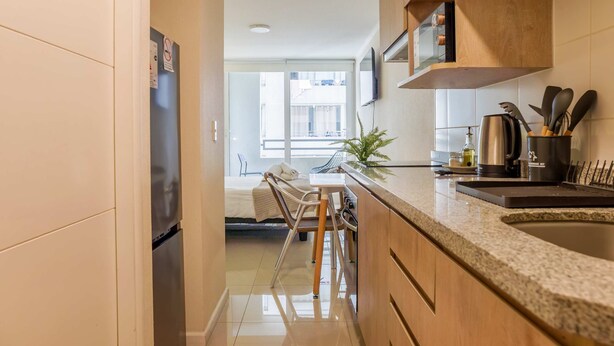 Una cucina moderna con forno integrato, un'area pranzo con una sedia e un tavolo, e vista su un balcone.