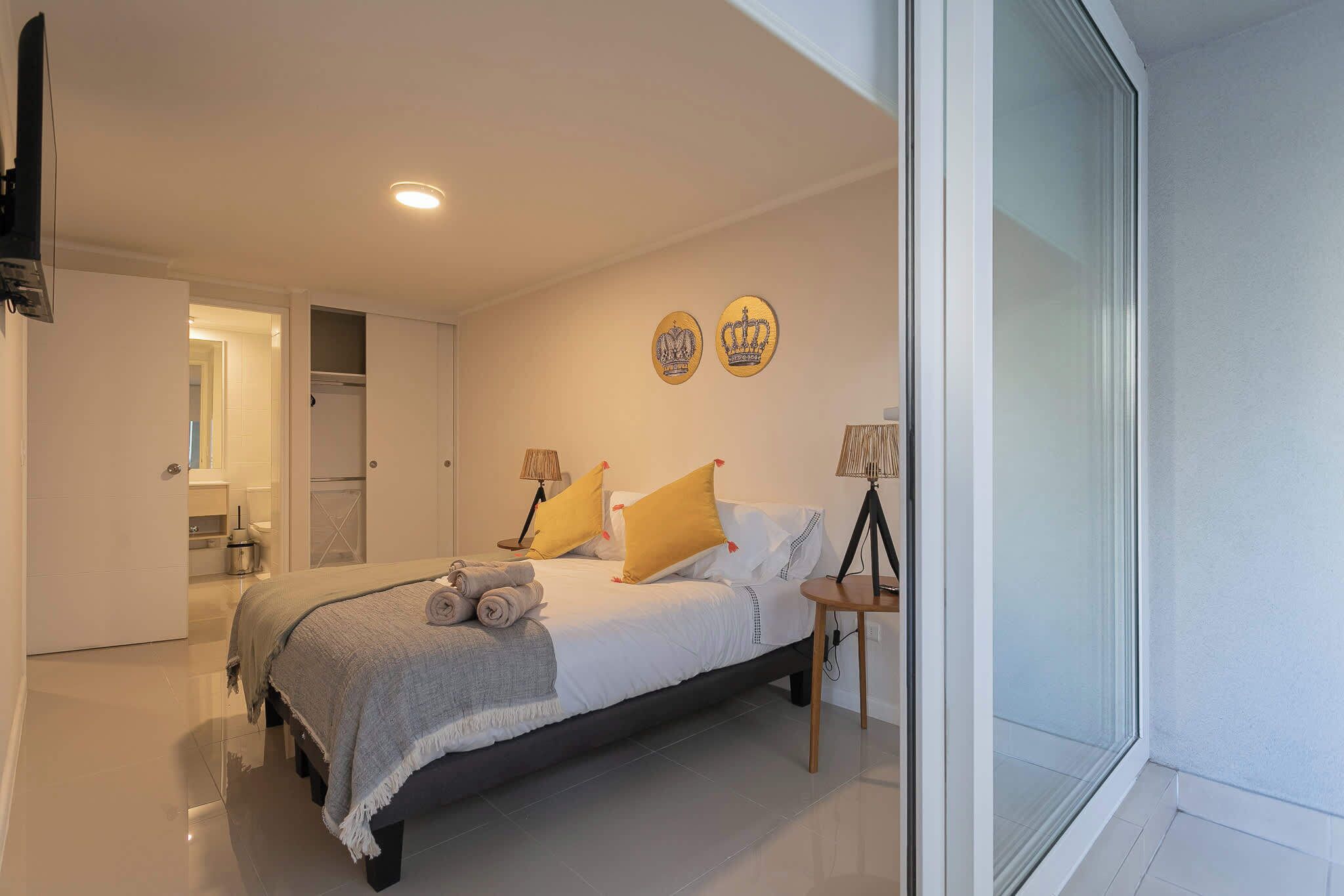Een moderne slaapkamer met een bed, bedlampen en een raam.