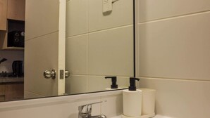 Un baño con lavamanos blanco, espejo e inodoro.
