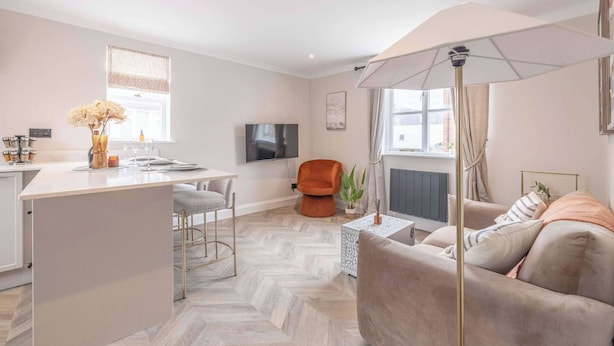 A modern living space with a kitchen island, a sofa, a TV, and a dining area.