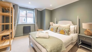 A bedroom with a bed, bedside tables, a wardrobe, and a window.