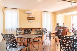 A dining area with a long table and chairs, a clock on the wall, and a window with curtains. - La Villetta nel parco (Rome)