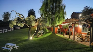 A well-maintained garden with a picnic table, a hammock, and a pergola with seating.