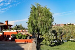 A patio area with a hanging lamp, a bench, and a view of a residential neighborhood. - La Villetta nel parco (Rome)