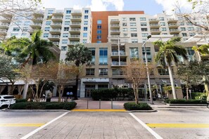 A multi-story hotel with a central courtyard, palm trees, and a storefront. - 1BR Miami Retreat w/BBQ, Pool, & Skyline Views (Miami)