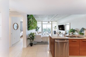 A modern kitchen with a large island, stainless steel appliances, and a view to the outside.