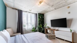 A modern bedroom with a bed, a TV, a desk, and a green wall. - 1BR Miami Retreat w/BBQ, Pool, & Skyline Views (Miami)