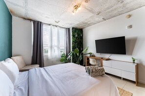 A modern bedroom with a bed, a TV, a desk, and a green wall. - 1BR Miami Retreat w/BBQ, Pool, & Skyline Views (Miami)
