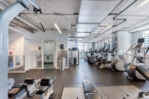 A gym with various exercise equipment, including treadmills and weight machines, and a visible door leading to another room.