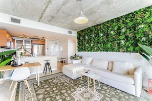 A modern living space with a white sofa, a dining area, and a kitchen.