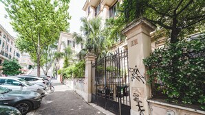 Eine schmale Straße gesäumt von parkenden Autos und einem verschlossenen Eingang mit Graffiti.