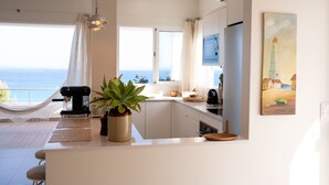 Una cocina moderna con vista al mar, una hamaca y un cuadro de un faro.