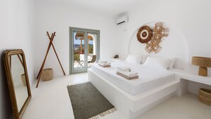 Un dormitorio minimalista con una cama grande, un espejo, un ventilador de pie y vistas al exterior.