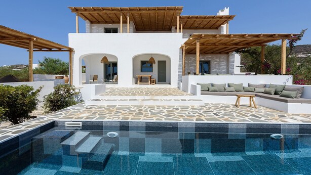 Una villa moderna con piscina, mobiliario exterior y vistas al paisaje.