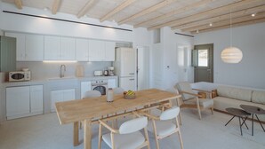 Una cocina moderna con armarios blancos, una mesa de comedor de madera y un diseño minimalista.