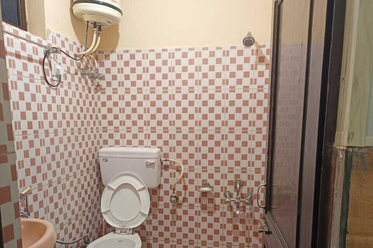 A small bathroom with a toilet, sink, and a water heater mounted on the wall.