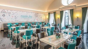 A restaurant with teal chairs and white tables, a mural with food illustrations, and a round skylight. - Vila Gale Casas D'Elvas Historic Hotel (Elvas)
