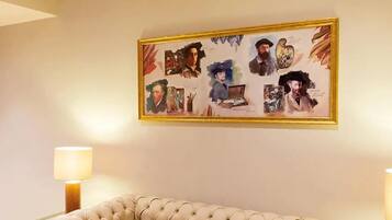 Una habitación con un gran collage enmarcado en la pared, un sofá con capitoné y dos lámparas de pie.