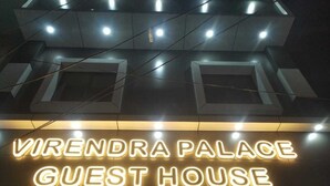 Een bord met de tekst 'VIRENDA PALACE GUEST HOUSE', met verlichte letters en een modern architectonisch ontwerp.