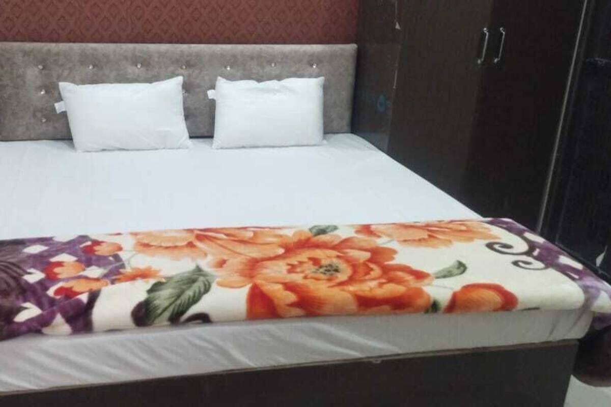 A bed with a floral bedspread, two white pillows, and a grey headboard.