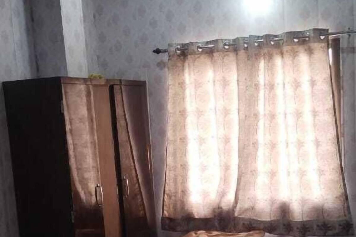 A bedroom with a bed, curtains, a wardrobe, and a ceiling fan.