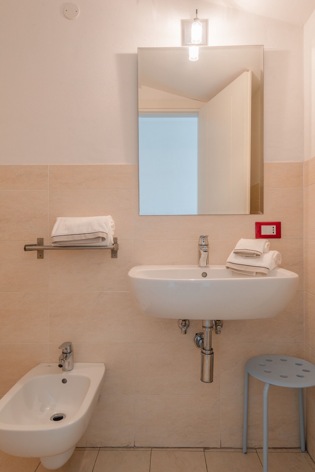 A bathroom with a white sink, a bidet, a mirror, and a towel rack.