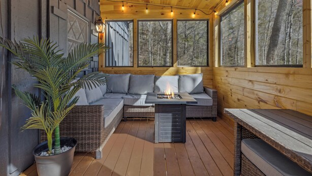 A cozy outdoor seating area with a fire pit, a sofa, and a dining table. - High Top Cabin with King Beds, Fire Pits, Hot Tub, Arcade, 🐻 Kids’ Clubhouse (Sevierville)