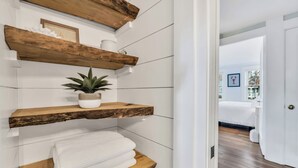 Ein Badezimmer mit Holzböden, einer Topfpflanze und ordentlich gefalteten Handtüchern.