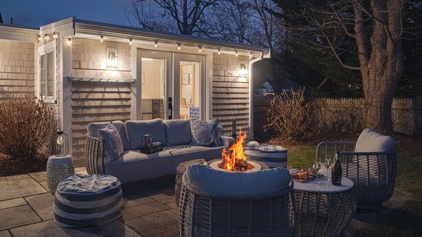 Eine Terrasss mit Feuerstelle, Sitzgelegenheiten und einem kleinen Tisch mit Speisen und Getränken.