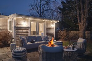 An outdoor patio with a fire pit, seating, and a small table with food and drinks. - The Cape Codder: Large Yard, Steps to Town & Beach (Harwich)