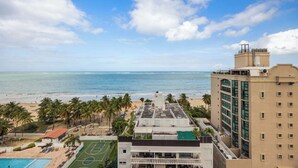 A hotel with a rooftop pool, a tennis court, and a view of the beach and ocean.