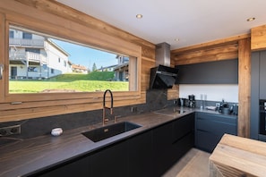Eine moderne Küche mit einem großen Fenster, dunklen Schränken und einem eingebauten Herd.
