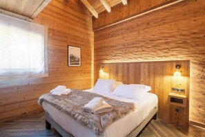 Ein Schlafzimmer einer Holzhütte mit einem Bett, zwei Nachttischlampen und einem gerahmten Bild an der Wand.