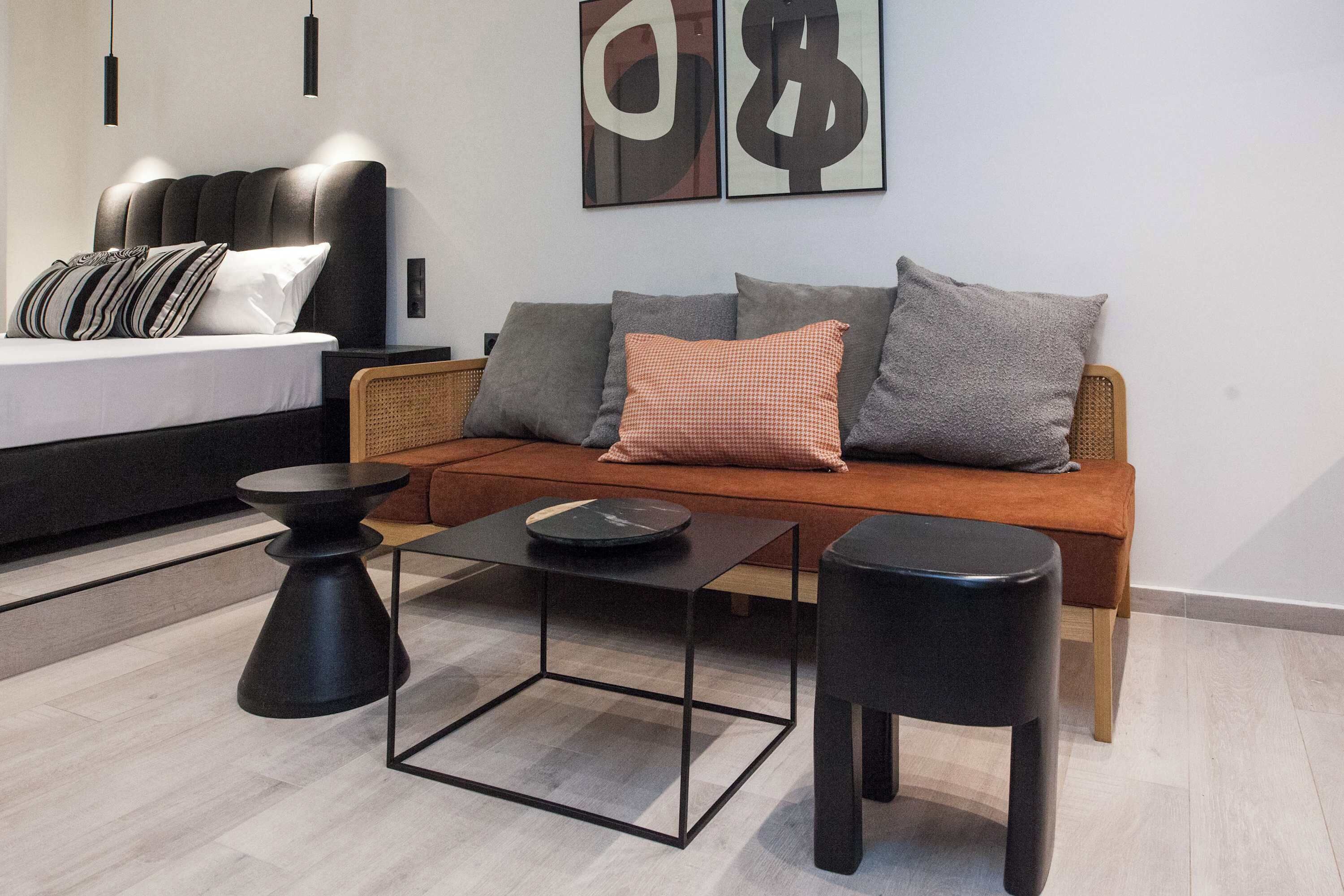 Een moderne woonkamer met een bank, twee bijzettafels en een bed met kussens.