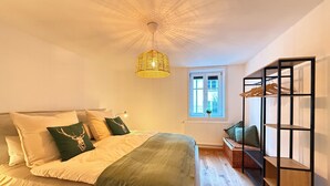 Ein Schlafzimmer mit Bett, einer Pendelleuchte, einem Fenster und einer integrierten Regaleinheit.