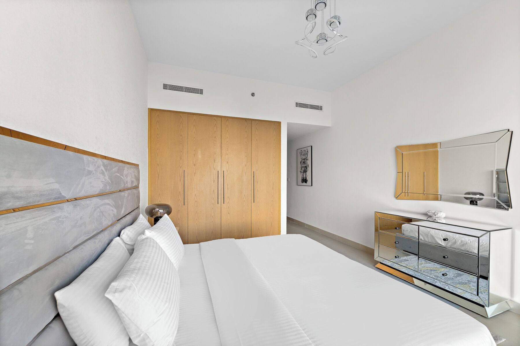 Ein modernes Schlafzimmer mit einem großen Bett, einem Holzschrank und einer Schminkkommode mit Spiegel.