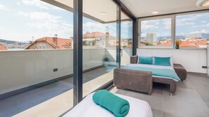 A balcony with a bed, a sofa, and a view of the cityscape. - Villa Muller Apartments (Split)
