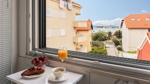 A balcony with a table, a croissant, a cup of coffee, and a glass of orange juice. - Villa Muller Apartments (Split)