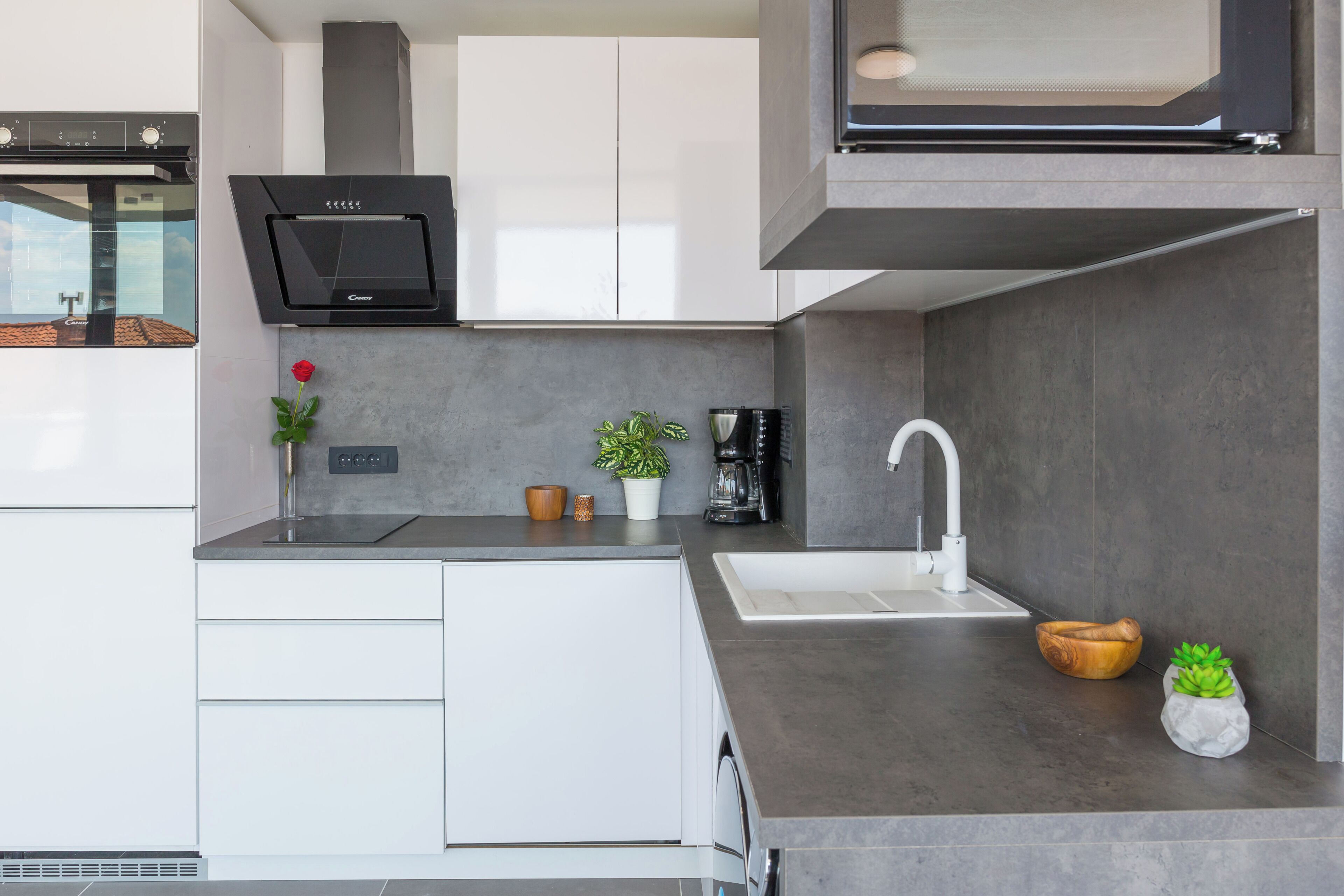A modern kitchen with a built-in oven, a coffee machine, and a sink.