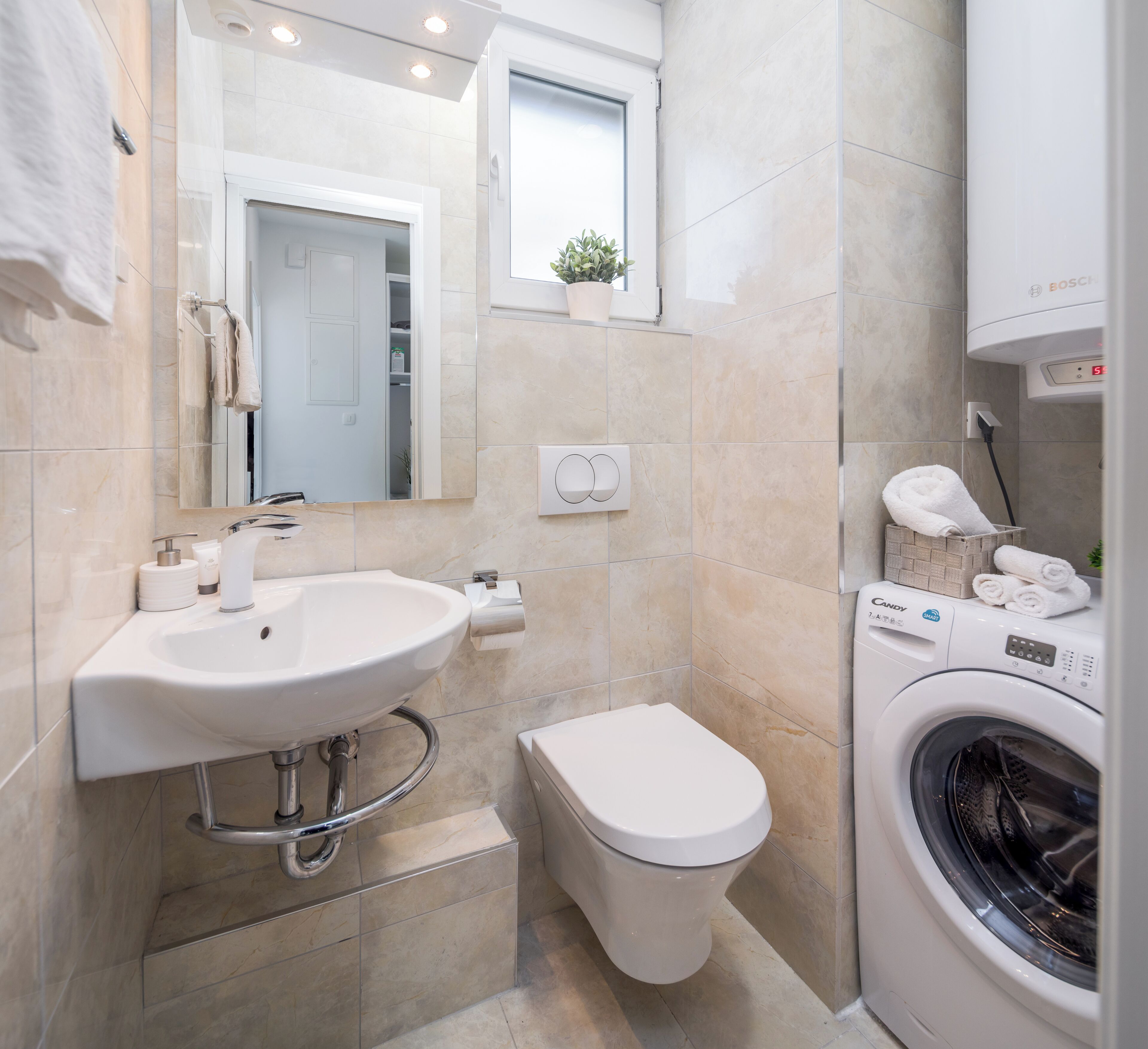 A bathroom with a sink, toilet, and washing machine.